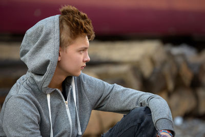 Man looking away while sitting outdoors