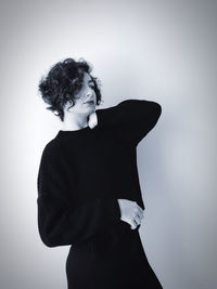 Teenage girl looking away while standing against white background