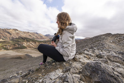 Woman smiling sitting with camera in the wind, in landmannalaugar