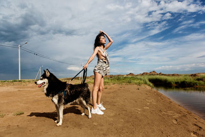 Full length of woman with dog against sky