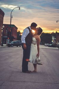 Friends on street in city against sky during sunset