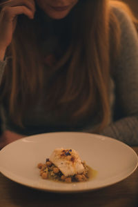 Midsection of woman with food plate on table