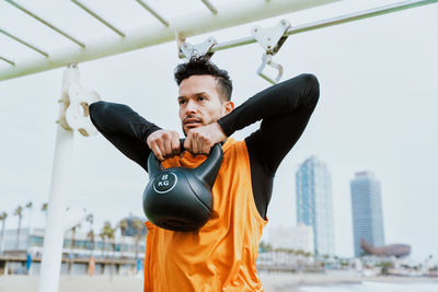 Young man exercising with kettlebell in gym