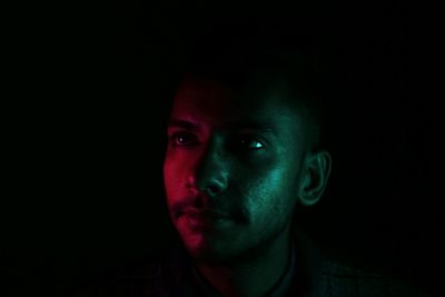 Close-up portrait of young man against black background