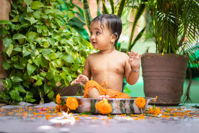 Cute toddler baby boy bathing in decorated bathtub at outdoor from unique perspective