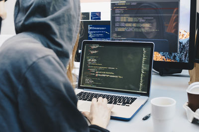 Side view of computer programmer programming on laptop at desk in office