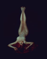 Digital composite image of woman lying against black background