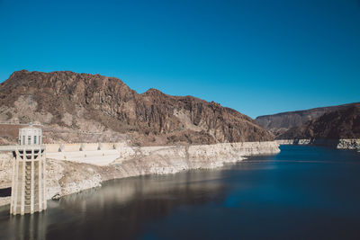 Hoover dam by colorado river against clear blue sky
