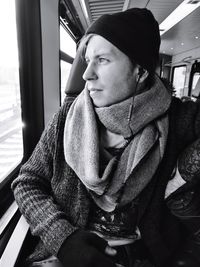 Young man looking through window while traveling in train