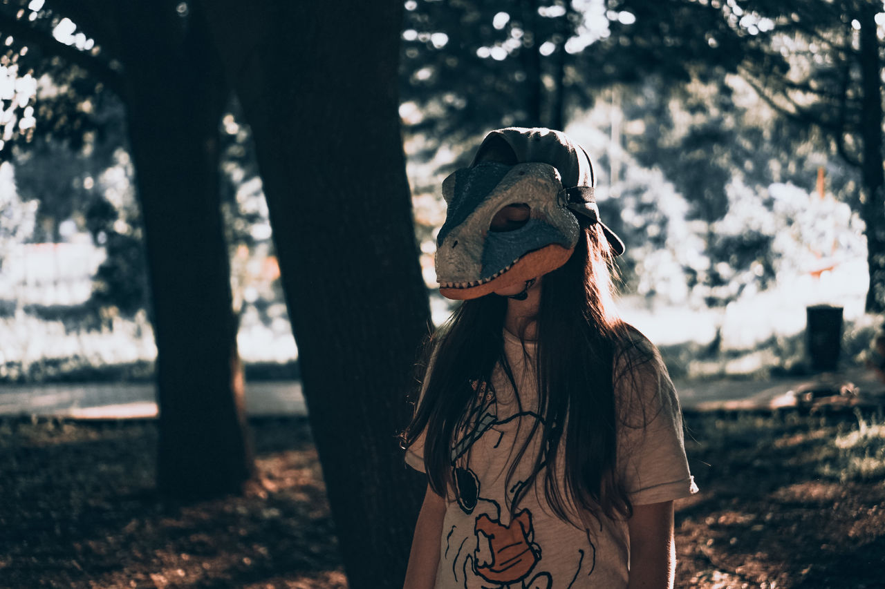 one person, tree, nature, spring, adult, women, plant, lifestyles, leisure activity, focus on foreground, clothing, land, young adult, standing, day, outdoors, portrait, fashion, front view, long hair, forest, waist up, hairstyle, hat, sunlight, casual clothing, darkness, black, person