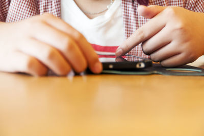 Midsection of child holding smart phone on table