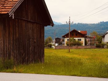 House on field by houses against sky