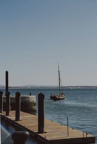 Sailboats on sea against clear sky