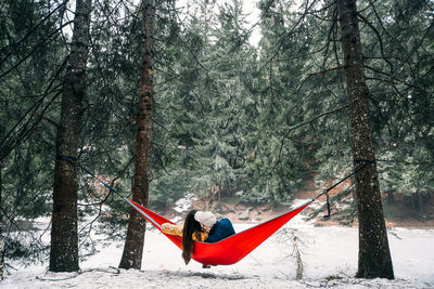 Couple romancing in hammock at forest during winter