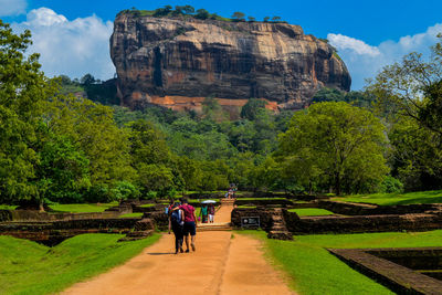 People walking on mountain road against sky