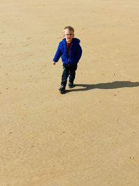 Full length portrait of boy walking on sand at beach