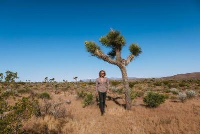 Man standing by tree on field against sky