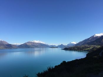 Scenic view of lake and mountains against clear sky