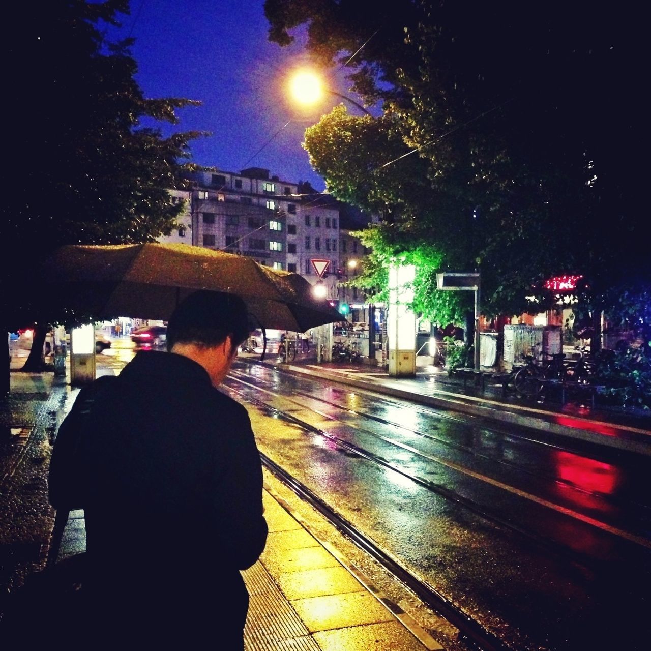 illuminated, night, lifestyles, building exterior, rear view, city, men, built structure, architecture, leisure activity, street, city life, person, walking, motion, standing, road, silhouette