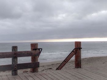 Pier on sea against cloudy sky