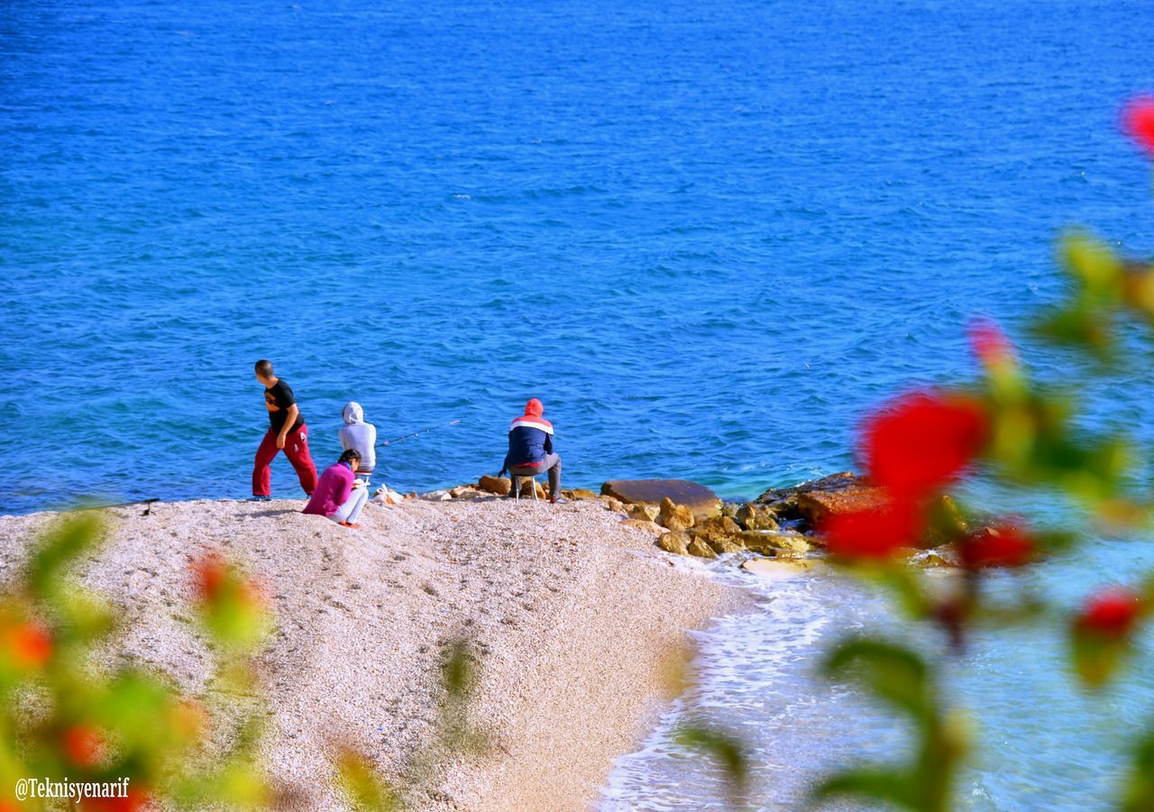 PEOPLE ON BEACH AGAINST SEA