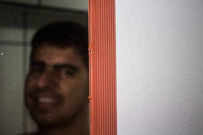 Portrait of young man looking through window