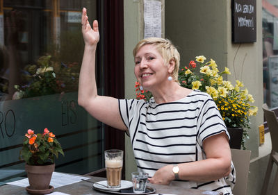 Portrait of young woman using mobile phone while sitting on table