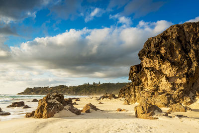 Rock formations on beach against sky