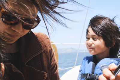 Boy wearing life jacket while traveling in sailboat with parents