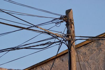 Low angle view of electricity pylon against clear sky