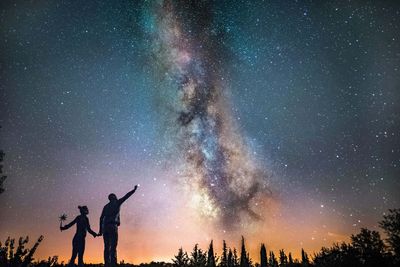 Silhouette couple standing against star field 