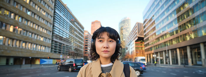 Portrait of young woman standing in city