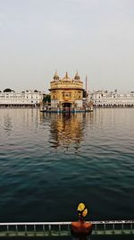 Golden temple by pond against sky