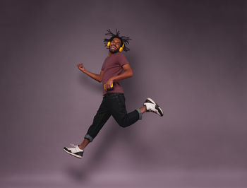 Low angle view of man jumping against gray background