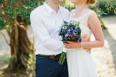 Midsection of couple holding flower bouquet