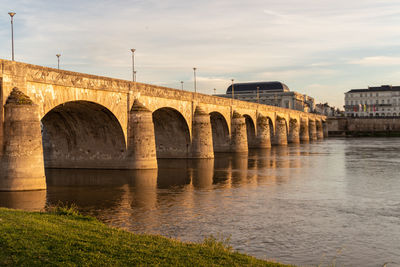 Arch bridge over river against sky