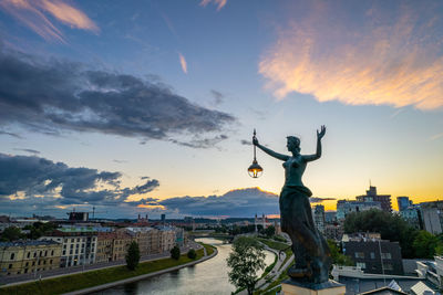 Rear view of man with arms outstretched standing on road against sky