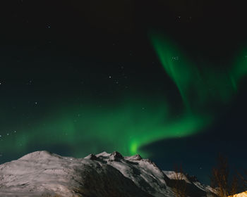 Low angle view of snowcapped mountain against sky at night