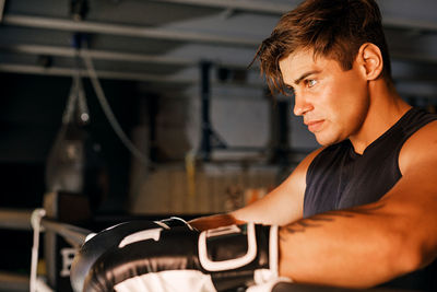 Side view of young man looking at camera