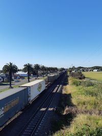 Train on railroad track against clear blue sky