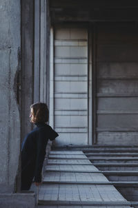 Side view of woman standing by columns below bridge