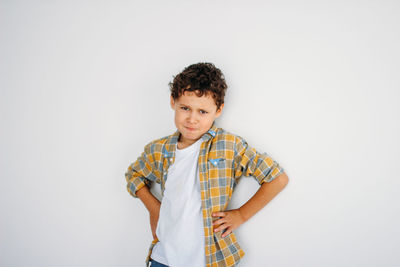 Portrait of angry boy standing against wall at home