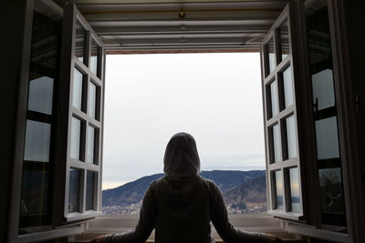 Rear view of woman looking through window