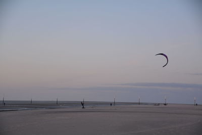 Person kiteboarding at beach against sky during sunset