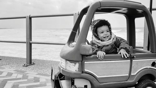 Little curly boy sitting in toy car.