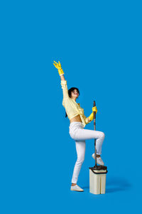 Low angle view of woman standing against clear blue sky