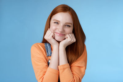 Portrait of a smiling young woman against blue background