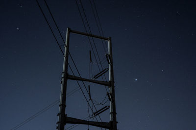 Low angle view of electricity pylon against clear sky at night