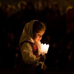 Close-up of cute girl holding illuminated artificial flower at night