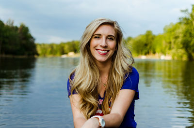Portrait of smiling young woman against lake